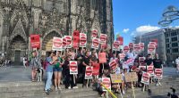 “We Are Today… WGA!” German Writers Show Strike Solidarity At Cologne Cathedral Protest