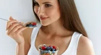 woman eating fresh berries, parfait, concept of how to lose 10 pounds quickly