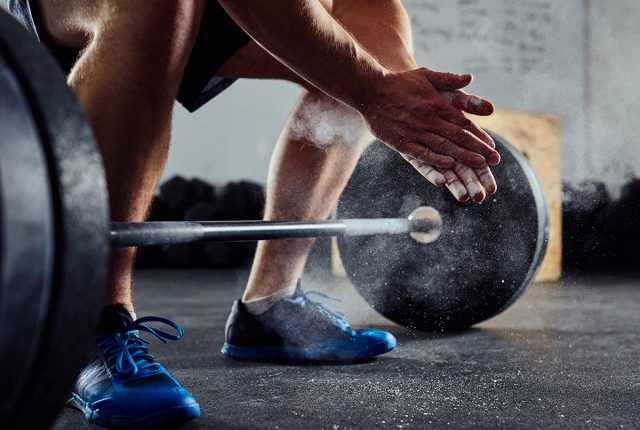 man getting ready to lift heavy dumbbell at the gym