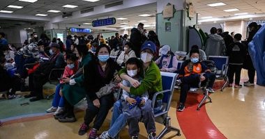 Children and their parents wait at an outpatient area in a children's hospital in Beijing as the city's hospitals are overwhelmed with cases of a new virus