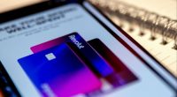 A smartphone screen displays the Revolut app with an image of two colourful credit cards, featuring the Revolut logo