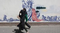 Residents stroll past an anti-US mural on a street in Tehran ahead of talks in Rome