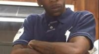 Man wearing a New York Yankees baseball cap and a navy polo shirt with red and white stripes.