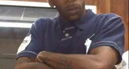 Man wearing a New York Yankees baseball cap and a navy polo shirt with red and white stripes.