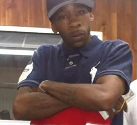 Man wearing a New York Yankees baseball cap and a navy polo shirt with red and white stripes.