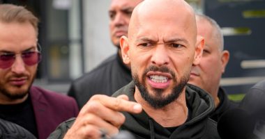 Andrew Tate speaking to the media outside a police station.