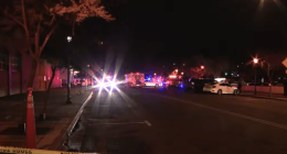 Nighttime street scene with emergency vehicles and police tape.