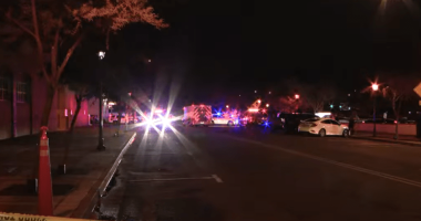 Nighttime street scene with emergency vehicles and police tape.