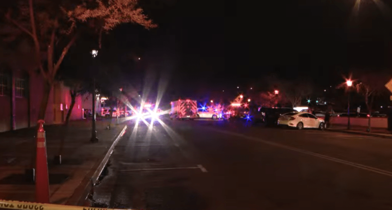 Nighttime street scene with emergency vehicles and police tape.