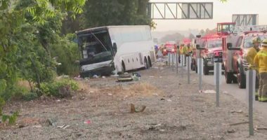Tour bus crash scene with emergency responders.