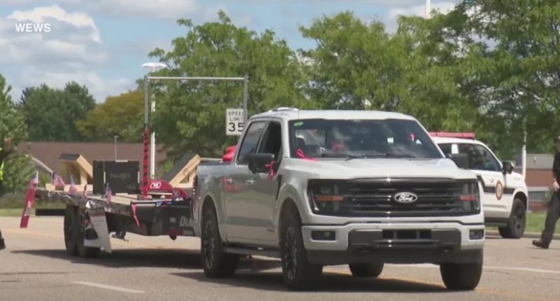 A silver pickup truck pulling a float in a parade.