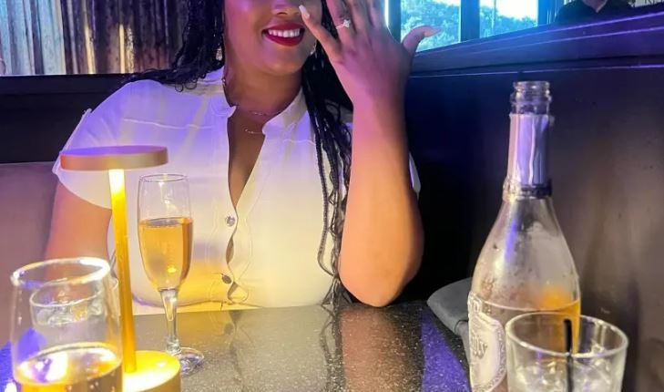 Woman showing off engagement ring at restaurant.