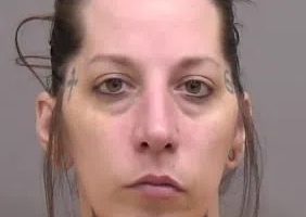 Mugshot of a woman with tattoos.