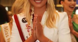 Miss England, Milla Magee, in a white dress and sash, performing a traditional greeting.