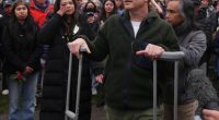 Man on crutches speaks at a vigil.