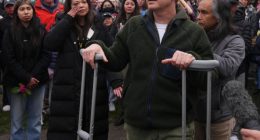 Man on crutches speaks at a vigil.