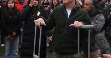 Man on crutches speaks at a vigil.