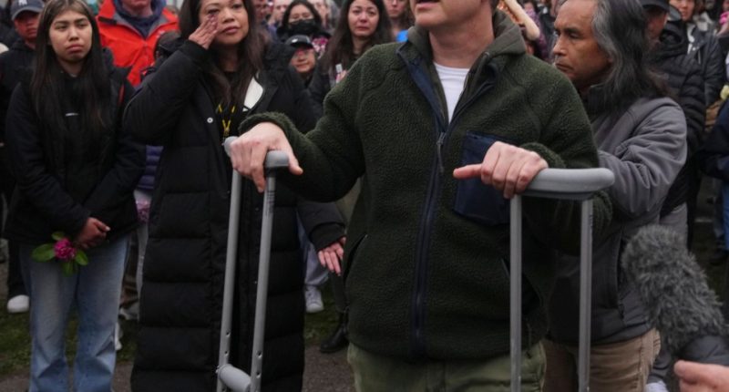 Man on crutches speaks at a vigil.