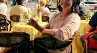 Woman sitting at an outdoor cafe in Milan, Italy, with a glass of white wine.