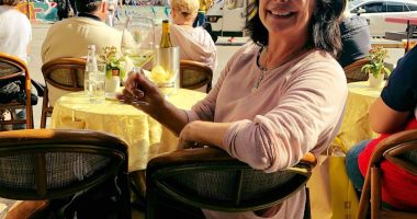 Woman sitting at an outdoor cafe in Milan, Italy, with a glass of white wine.