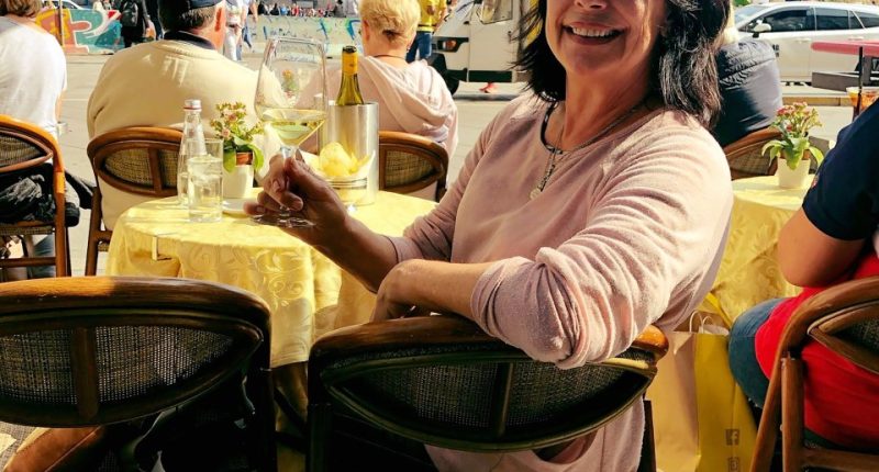 Woman sitting at an outdoor cafe in Milan, Italy, with a glass of white wine.