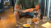Man sitting at a table with drinks and snacks.