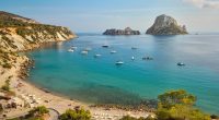 Cala d'Hort bay in Ibiza, Spain, with boats and the islands of Es Vedrà and Es Vedranell.