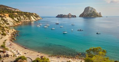 Cala d'Hort bay in Ibiza, Spain, with boats and the islands of Es Vedrà and Es Vedranell.