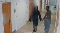 CCTV footage of two people walking down a prison corridor.