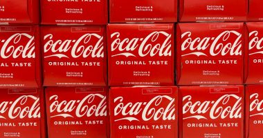 Close-up photo of multiple Coca-Cola 12-packs on a store shelf.