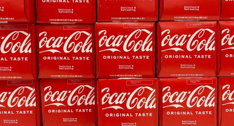 Close-up photo of multiple Coca-Cola 12-packs on a store shelf.