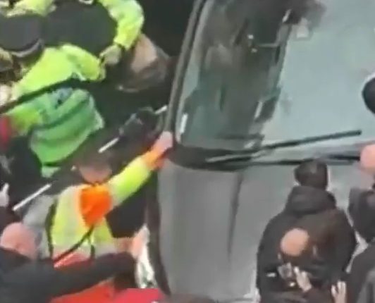 Police officers removing a driver from a car during a Liverpool parade.