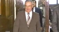 A man in a suit walks down a hallway.