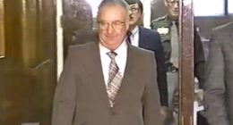 A man in a suit walks down a hallway.