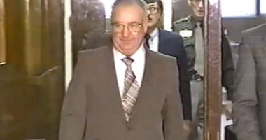 A man in a suit walks down a hallway.