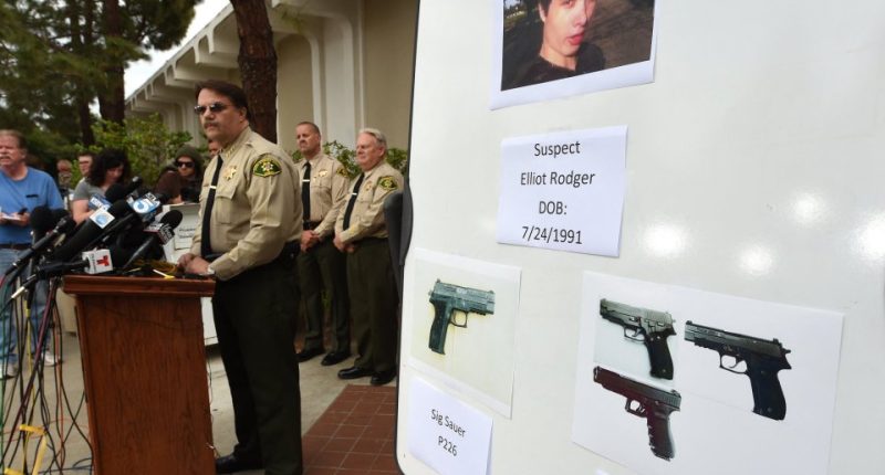 Photo of a press conference where law enforcement officials display photos of Elliot Rodger and the weapons used in the Isla Vista shooting.