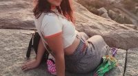Woman sitting on a rock with an umbrella.