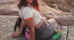 Woman sitting on a rock with an umbrella.
