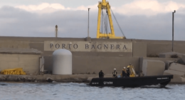 Small boat near Porto Bagnera harbor wall.