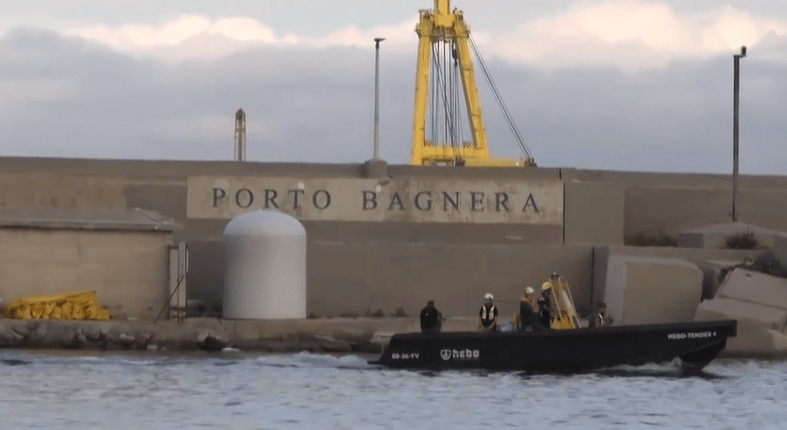 Small boat near Porto Bagnera harbor wall.