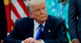 President Trump seated at a desk in the Oval Office.