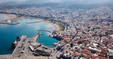 Aerial view of Heraklion, Crete, showing the city's harbor, coastline, and surrounding buildings.