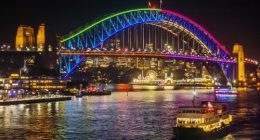 A ferry passes the Sydney Harbour Bridge, lit up in colourful lights as part of the Vivid Sydney festival.