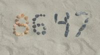 Seashells arranged to form the number 8647 in the sand.