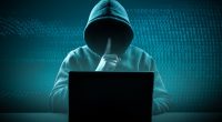 a person in a hoodie sitting in front of a laptop