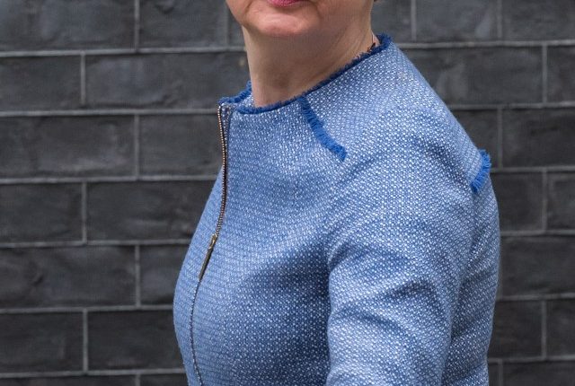 A woman in a blue jacket is being interviewed in front of a drawing of Big Ben.
