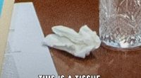 Image of a tissue, papers, and a glass on a table.