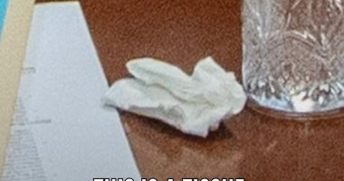 Image of a tissue, papers, and a glass on a table.