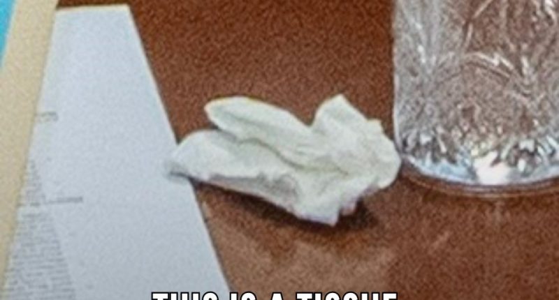 Image of a tissue, papers, and a glass on a table.