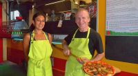 Two pizza makers holding a pizza.